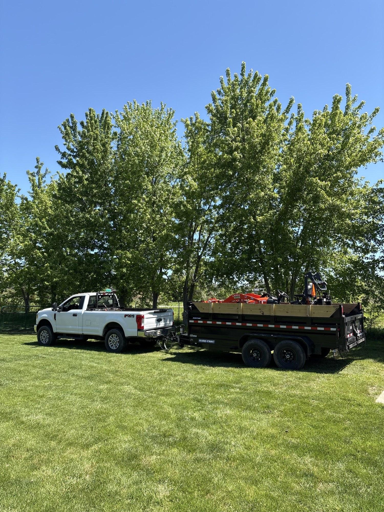 Steen's Lawn Care LLC truck and trailer loaded with mowing equipment parked on a lawn